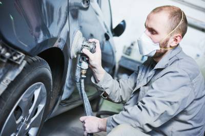 Mécanicien réparant efficacement la carrosserie d'une voiture abîmée